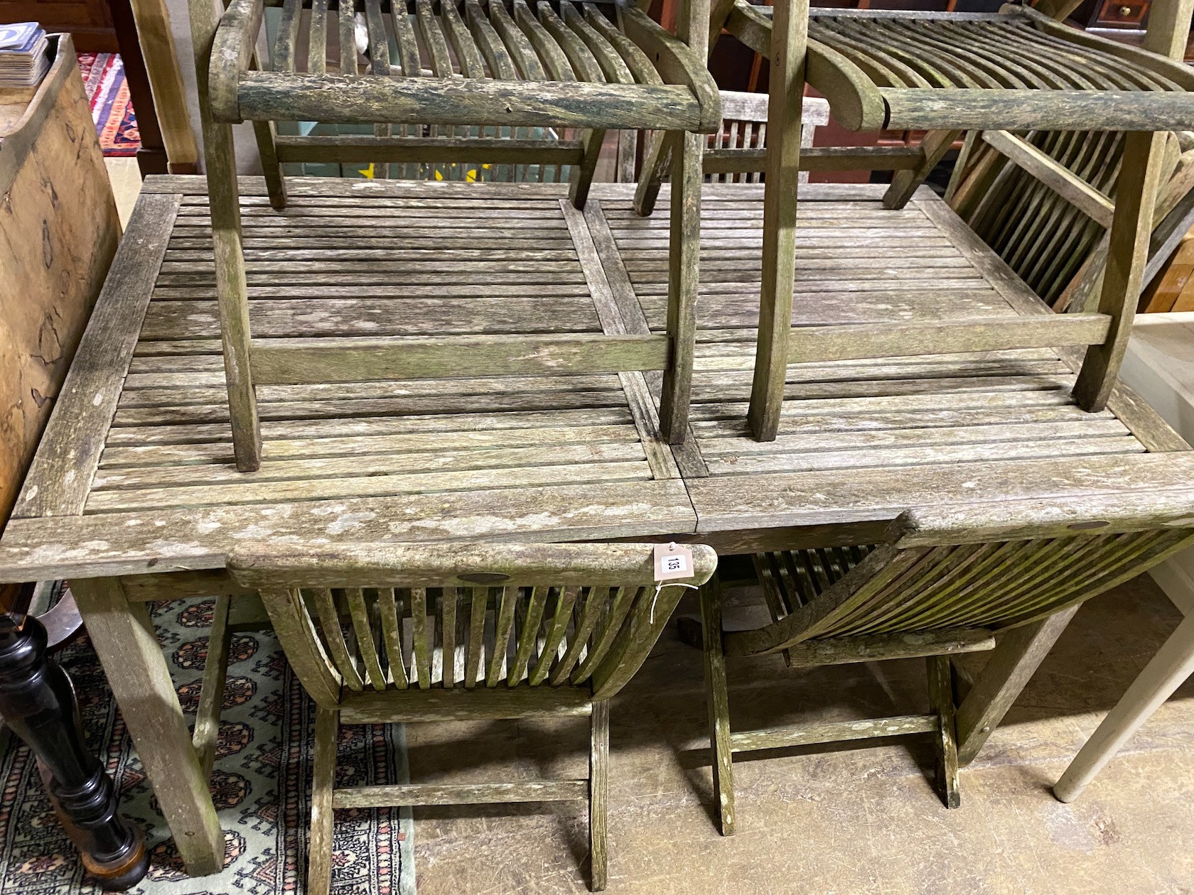 A rectangular weathered teak extending garden table, length 192cm extended, width 89cm, height 76cm together with eight teak folding garden chairs, two with arms